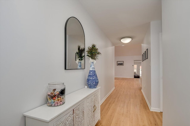 hall featuring light wood-type flooring and baseboards