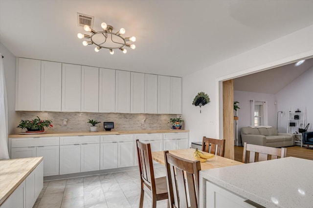 kitchen with marble finish floor, backsplash, visible vents, and white cabinetry