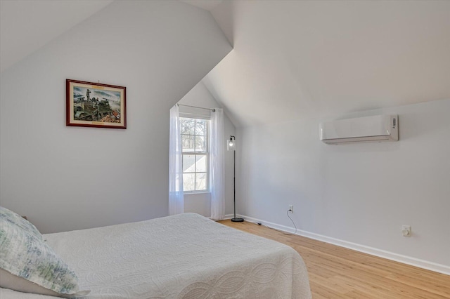 bedroom featuring a wall mounted air conditioner, vaulted ceiling, baseboards, and wood finished floors