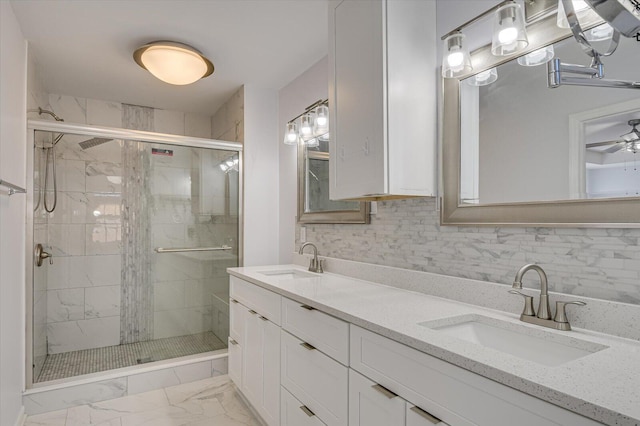 bathroom with marble finish floor, a sink, a shower stall, and decorative backsplash