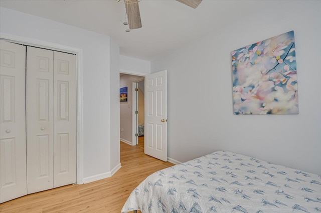 bedroom with ceiling fan, a closet, light wood-style flooring, and baseboards