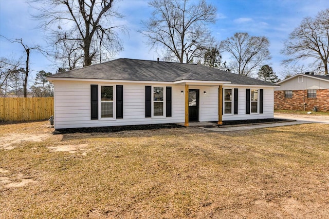 ranch-style house featuring a shingled roof, a front yard, and fence