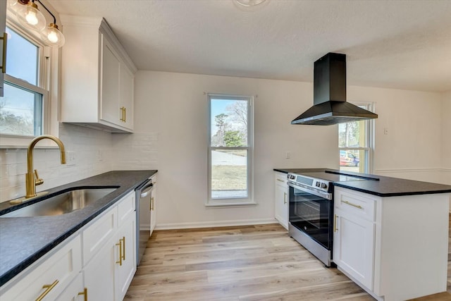 kitchen featuring island exhaust hood, a sink, light wood-style floors, appliances with stainless steel finishes, and decorative backsplash