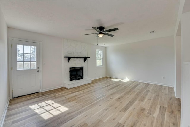 unfurnished living room featuring visible vents, baseboards, ceiling fan, light wood-type flooring, and a fireplace