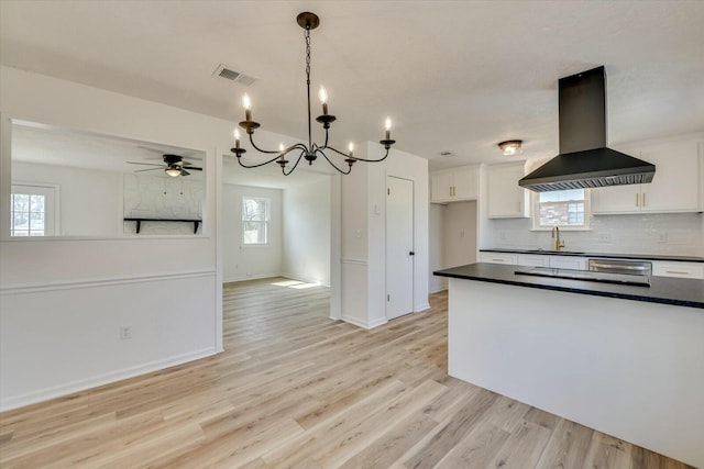 kitchen featuring dark countertops, white cabinets, visible vents, and island range hood