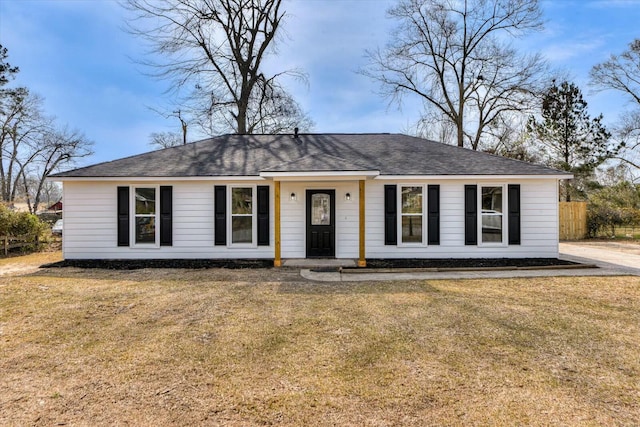 ranch-style home with a front yard, fence, and a shingled roof