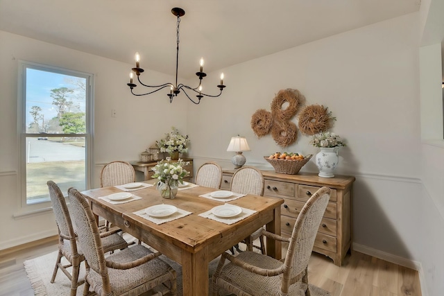 dining room featuring a chandelier, light wood finished floors, and baseboards