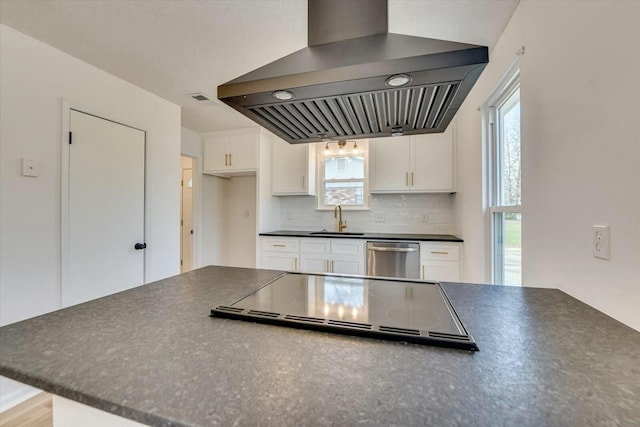 kitchen with dark countertops, backsplash, dishwasher, stovetop, and wall chimney exhaust hood