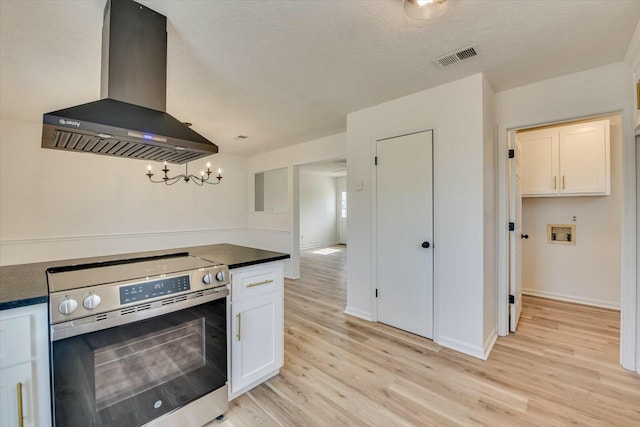 kitchen with dark countertops, visible vents, light wood finished floors, extractor fan, and stainless steel electric range oven