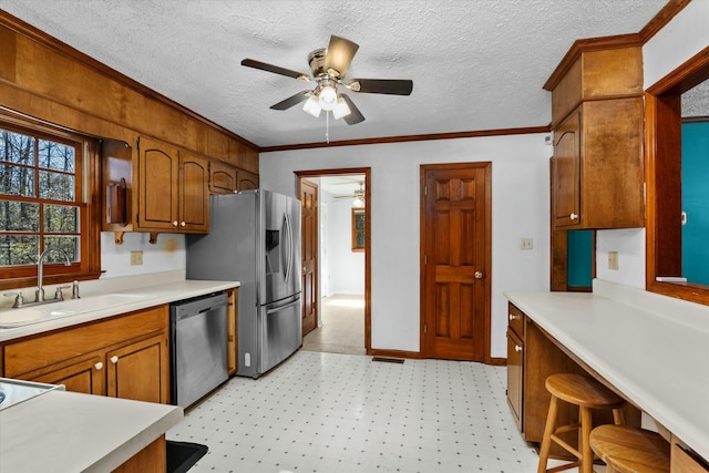 kitchen featuring ornamental molding, sink, stainless steel appliances, and a textured ceiling