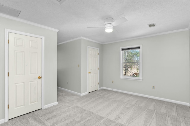 unfurnished bedroom featuring a textured ceiling, ceiling fan, light colored carpet, and ornamental molding