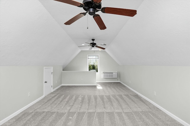 bonus room with lofted ceiling, a textured ceiling, a wall mounted AC, and light colored carpet