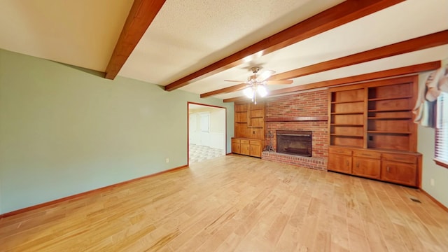 unfurnished living room featuring a fireplace, beam ceiling, light hardwood / wood-style flooring, ceiling fan, and a textured ceiling