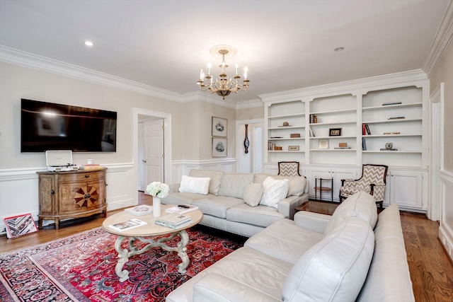 living area featuring wood finished floors, a chandelier, crown molding, a wainscoted wall, and a decorative wall