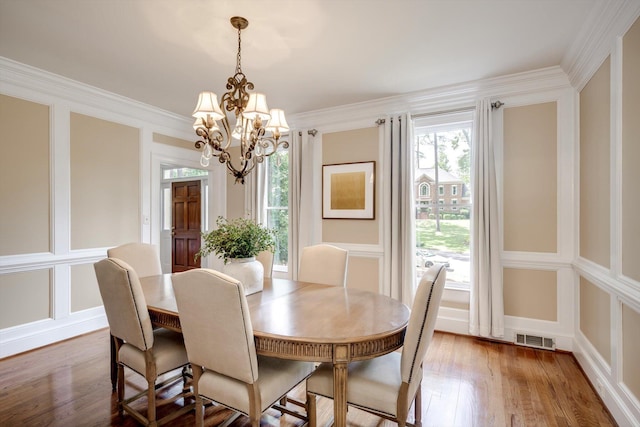 dining room featuring a chandelier, wood finished floors, a decorative wall, and crown molding