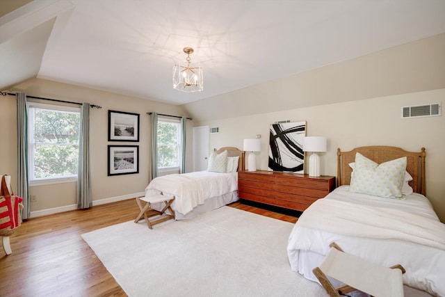 bedroom featuring lofted ceiling, a chandelier, wood finished floors, and baseboards