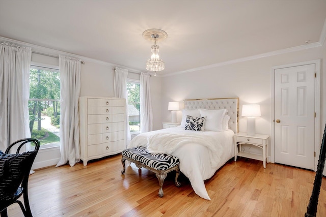 bedroom with multiple windows, ornamental molding, light wood-style floors, and a chandelier