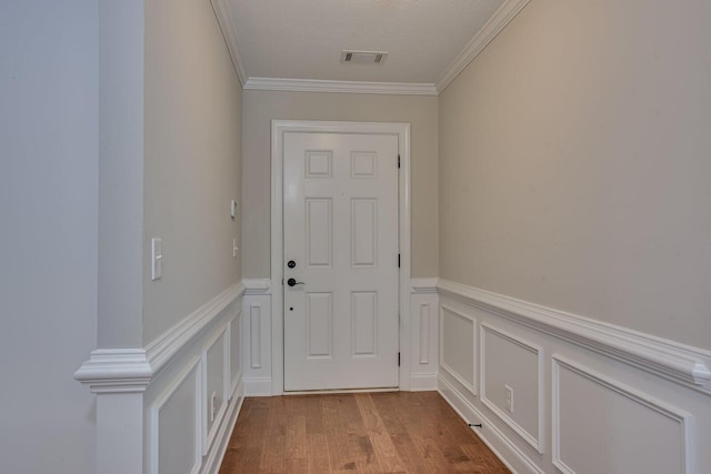 doorway to outside with light wood-type flooring, a textured ceiling, and ornamental molding