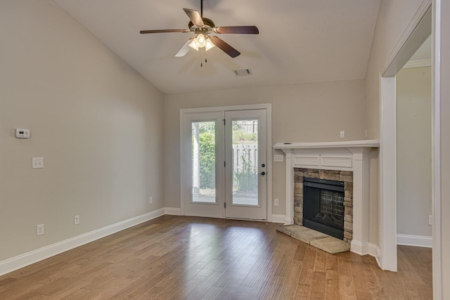 unfurnished living room featuring ceiling fan, a stone fireplace, lofted ceiling, and light hardwood / wood-style flooring