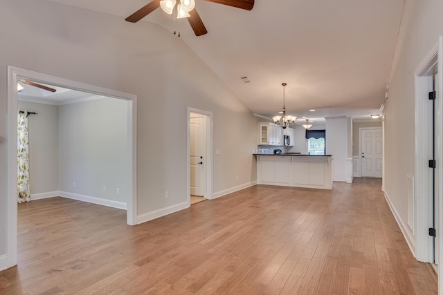 unfurnished living room with ceiling fan with notable chandelier, light wood-type flooring, and vaulted ceiling