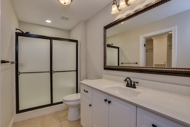 bathroom featuring tile patterned flooring, vanity, toilet, and walk in shower