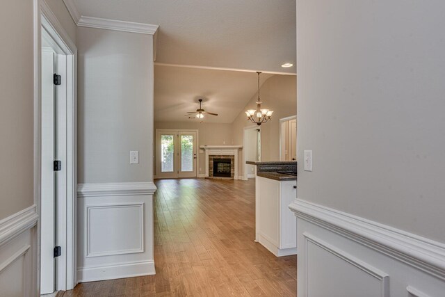 interior space featuring light hardwood / wood-style floors, ornamental molding, vaulted ceiling, and a notable chandelier