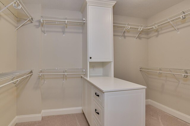 walk in closet featuring light colored carpet