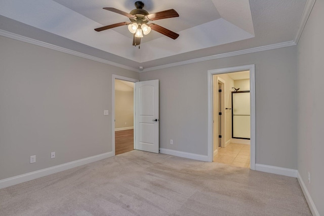 unfurnished bedroom with a raised ceiling, ceiling fan, crown molding, and light carpet