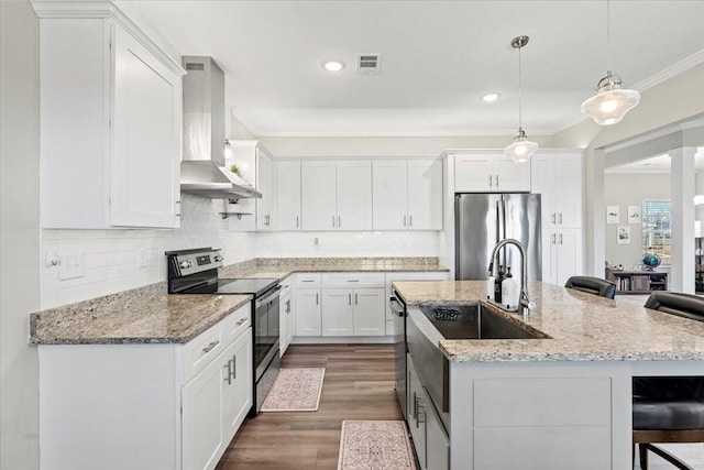 kitchen with backsplash, wall chimney range hood, ornamental molding, appliances with stainless steel finishes, and white cabinets