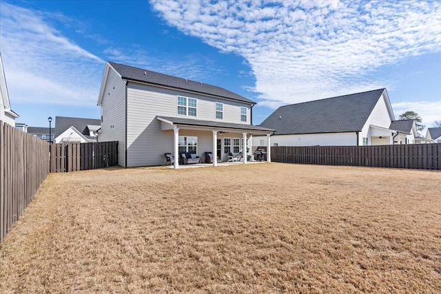 rear view of property featuring a yard, a patio area, and a fenced backyard