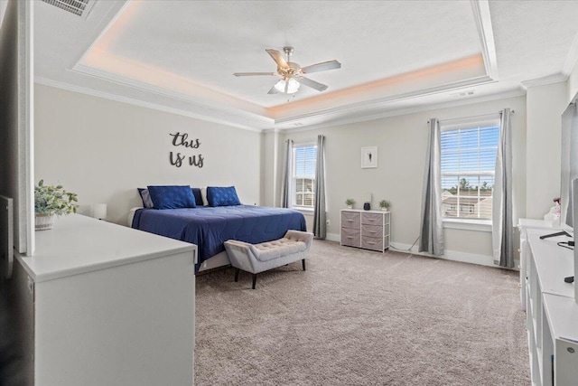 bedroom featuring light carpet, multiple windows, a raised ceiling, and baseboards