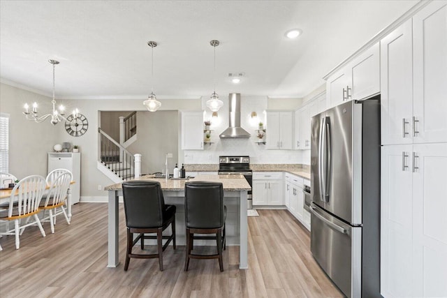 kitchen with white cabinetry, wall chimney exhaust hood, light wood-type flooring, and appliances with stainless steel finishes