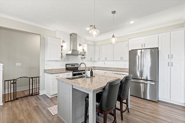 kitchen featuring light wood-type flooring, stainless steel appliances, wall chimney exhaust hood, and white cabinetry