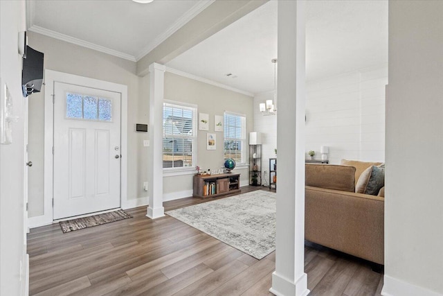 entrance foyer featuring ornate columns, baseboards, wood finished floors, and ornamental molding