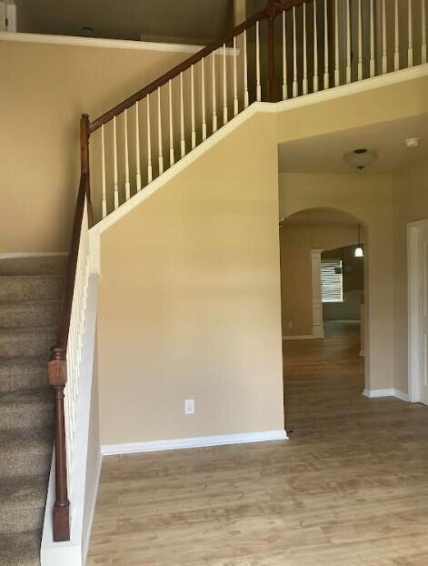 6066 Reynolds Cir, Grovetown, GA 30813 - staircase featuring arched walkways, wood finished floors, and a high ceiling