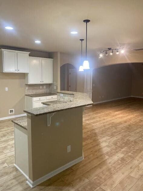 6066 Reynolds Cir, Grovetown, GA 30813 - kitchen with light wood-style flooring, white cabinets, light stone counters, decorative light fixtures, and a kitchen island