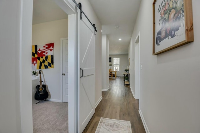 hallway featuring a barn door, recessed lighting, wood finished floors, and baseboards