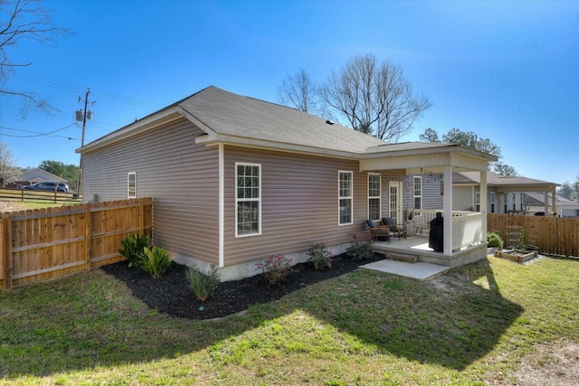 rear view of property featuring a yard, a patio area, and fence