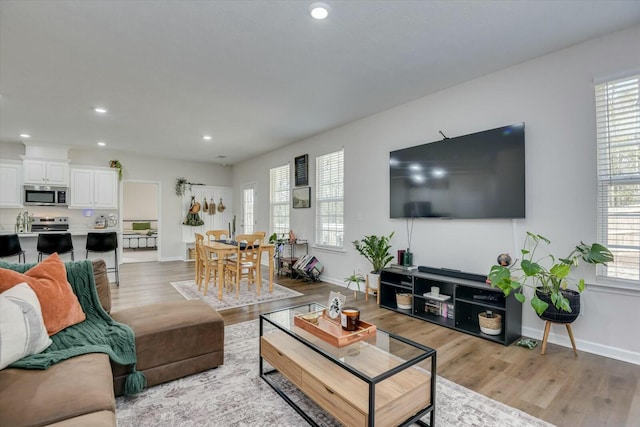 living room featuring light wood finished floors, recessed lighting, baseboards, and a wealth of natural light