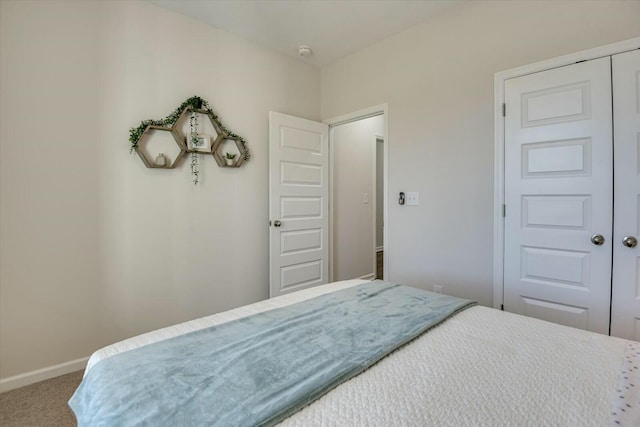 carpeted bedroom featuring baseboards and a closet