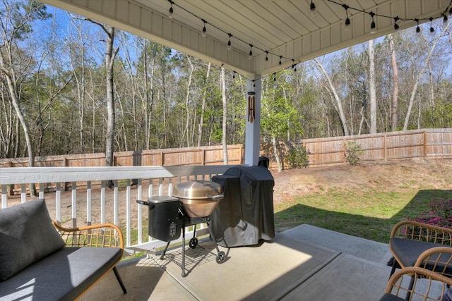 view of patio / terrace featuring grilling area, a wooded view, and a fenced backyard