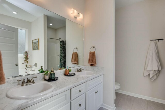 full bathroom with double vanity, toilet, baseboards, and a sink