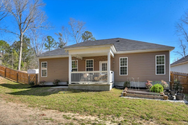 rear view of house with a garden, a lawn, a porch, and fence