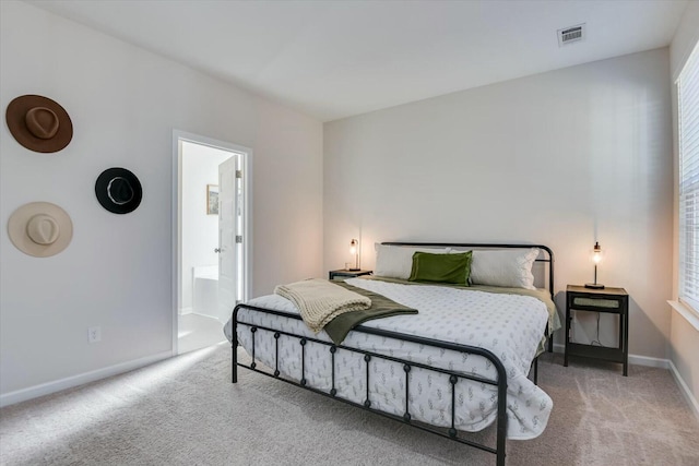 carpeted bedroom with visible vents, baseboards, and ensuite bath