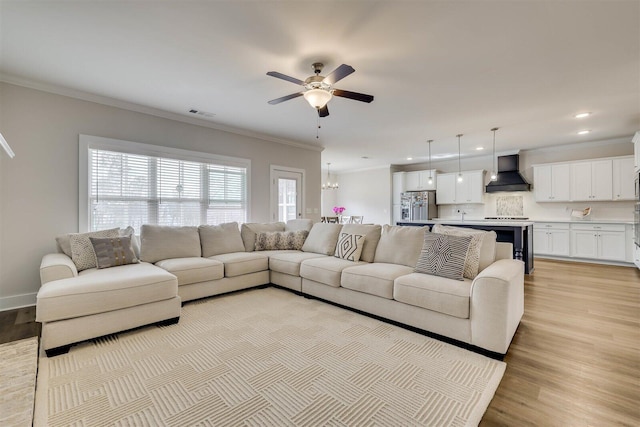 living room featuring recessed lighting, ornamental molding, light wood-style floors, baseboards, and ceiling fan with notable chandelier