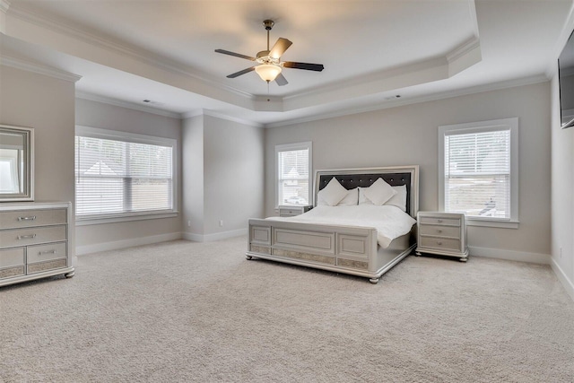 bedroom with baseboards, a raised ceiling, a ceiling fan, light colored carpet, and ornamental molding