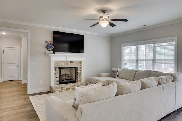 living area with baseboards, visible vents, wood finished floors, crown molding, and a fireplace