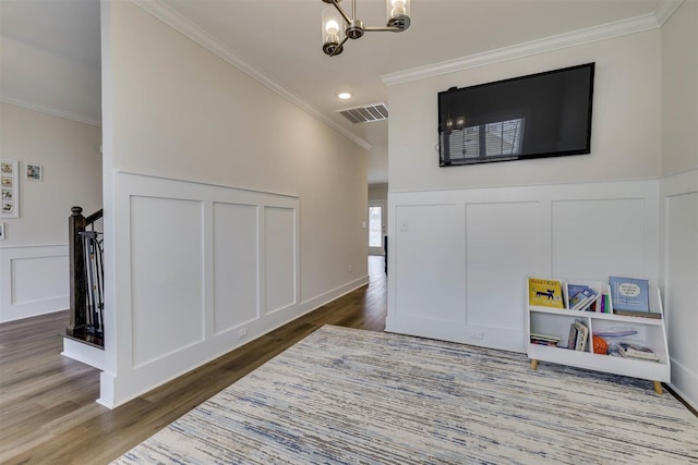 game room with ornamental molding, visible vents, a decorative wall, and dark wood-type flooring