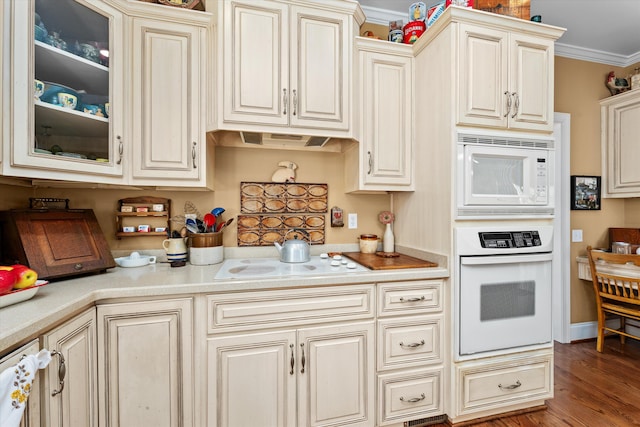 kitchen featuring cream cabinetry, wood-type flooring, white appliances, and ornamental molding