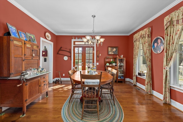 dining area featuring french doors, light wood-type flooring, ornamental molding, and a notable chandelier